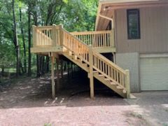 A house with a wooden deck and stairs leading up to it.