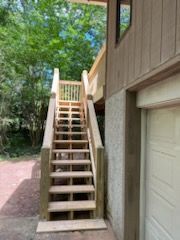 A wooden staircase leading up to a deck next to a garage.