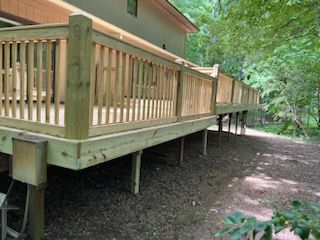 A wooden deck is sitting on top of a dirt hill next to a house.