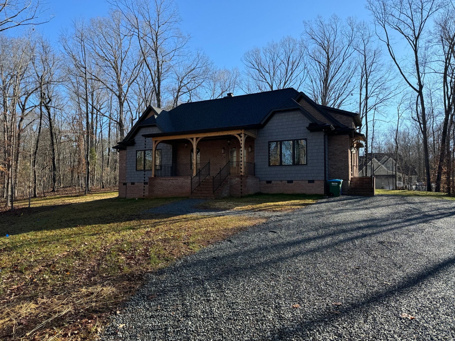 A house with a black roof is surrounded by trees