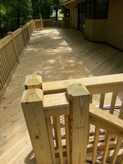A wooden deck with a railing and stairs leading to a house.