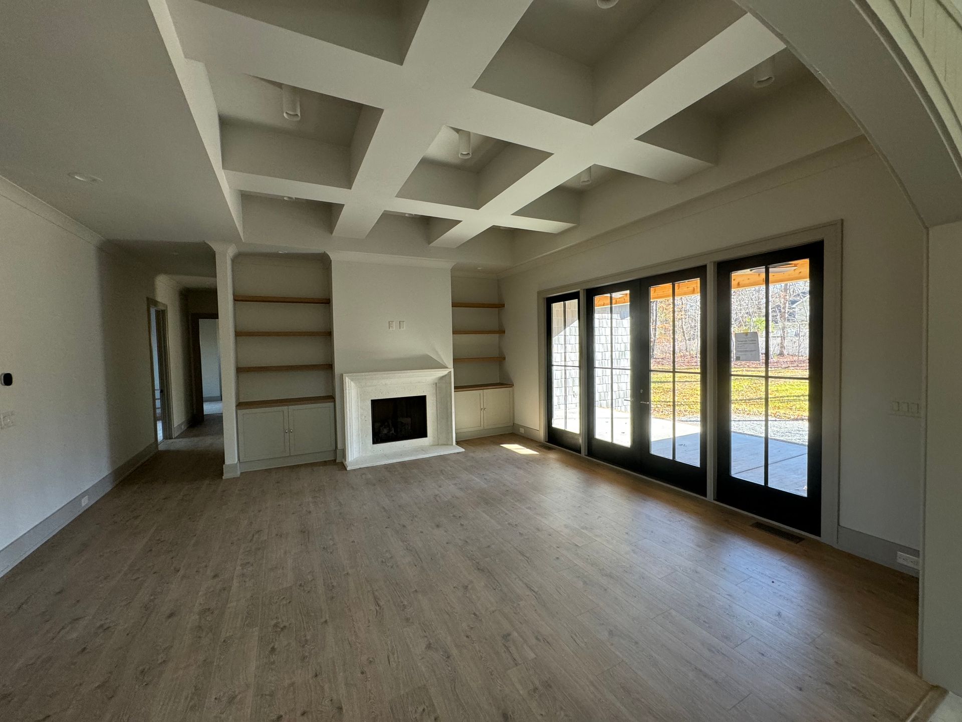 An empty living room with a fireplace and sliding glass doors.