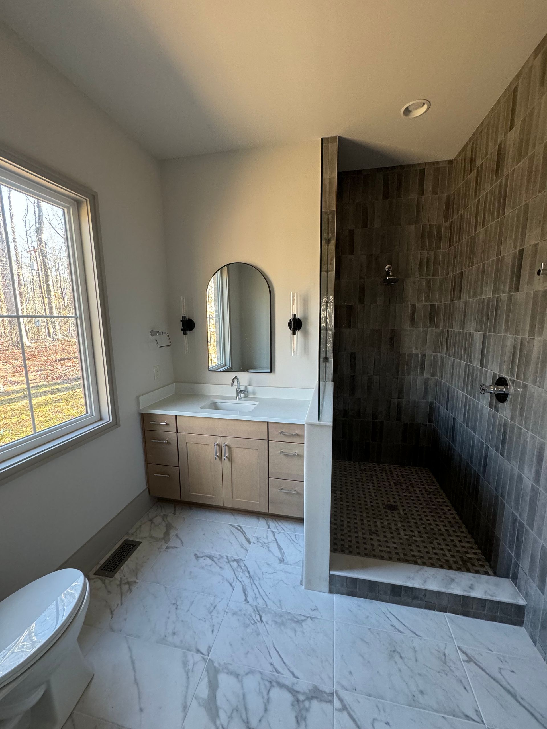 A bathroom with a toilet , sink , mirror and walk in shower.