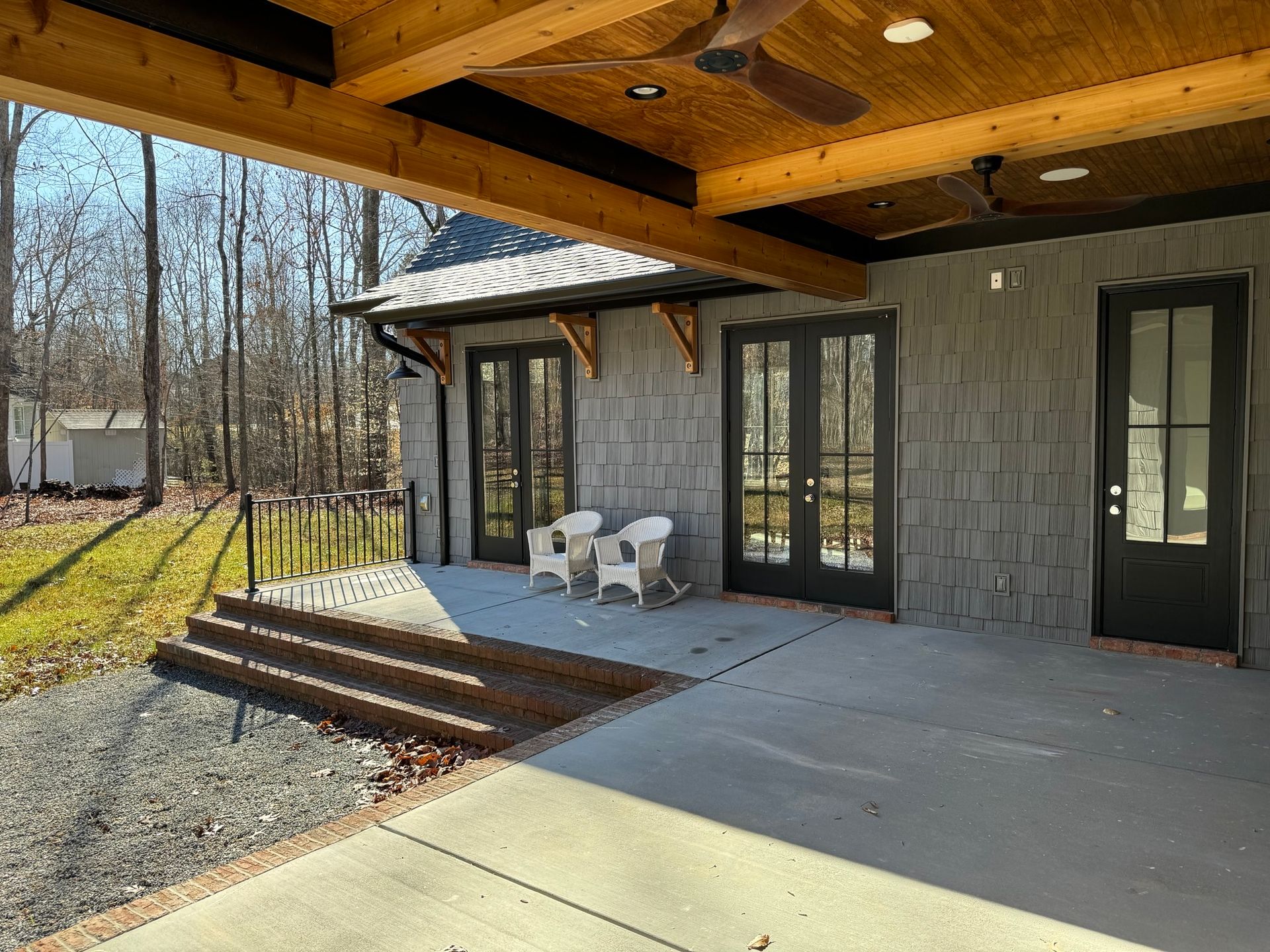 A patio with chairs and a ceiling fan in front of a house.