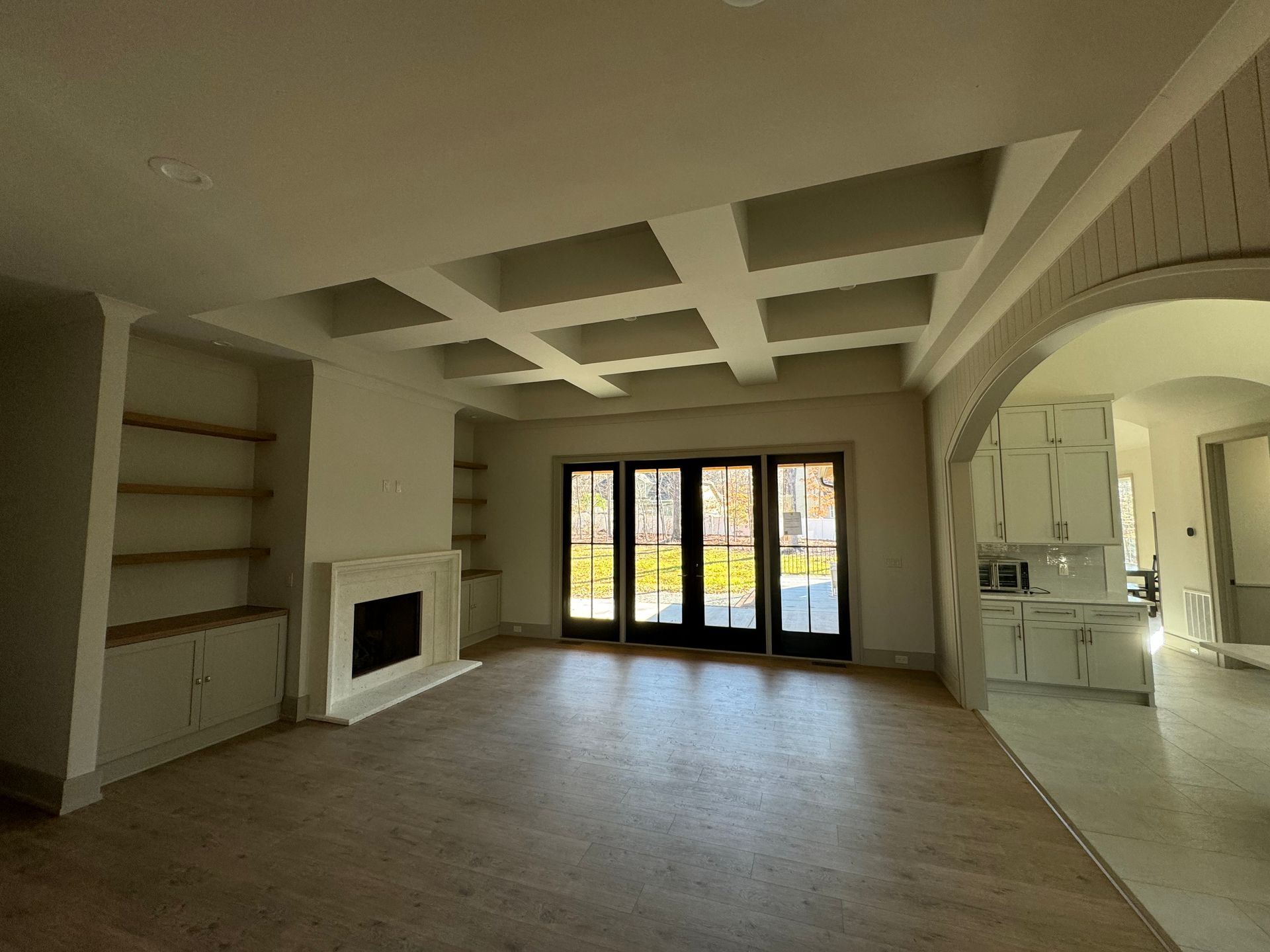 An empty living room with a fireplace and sliding glass doors.