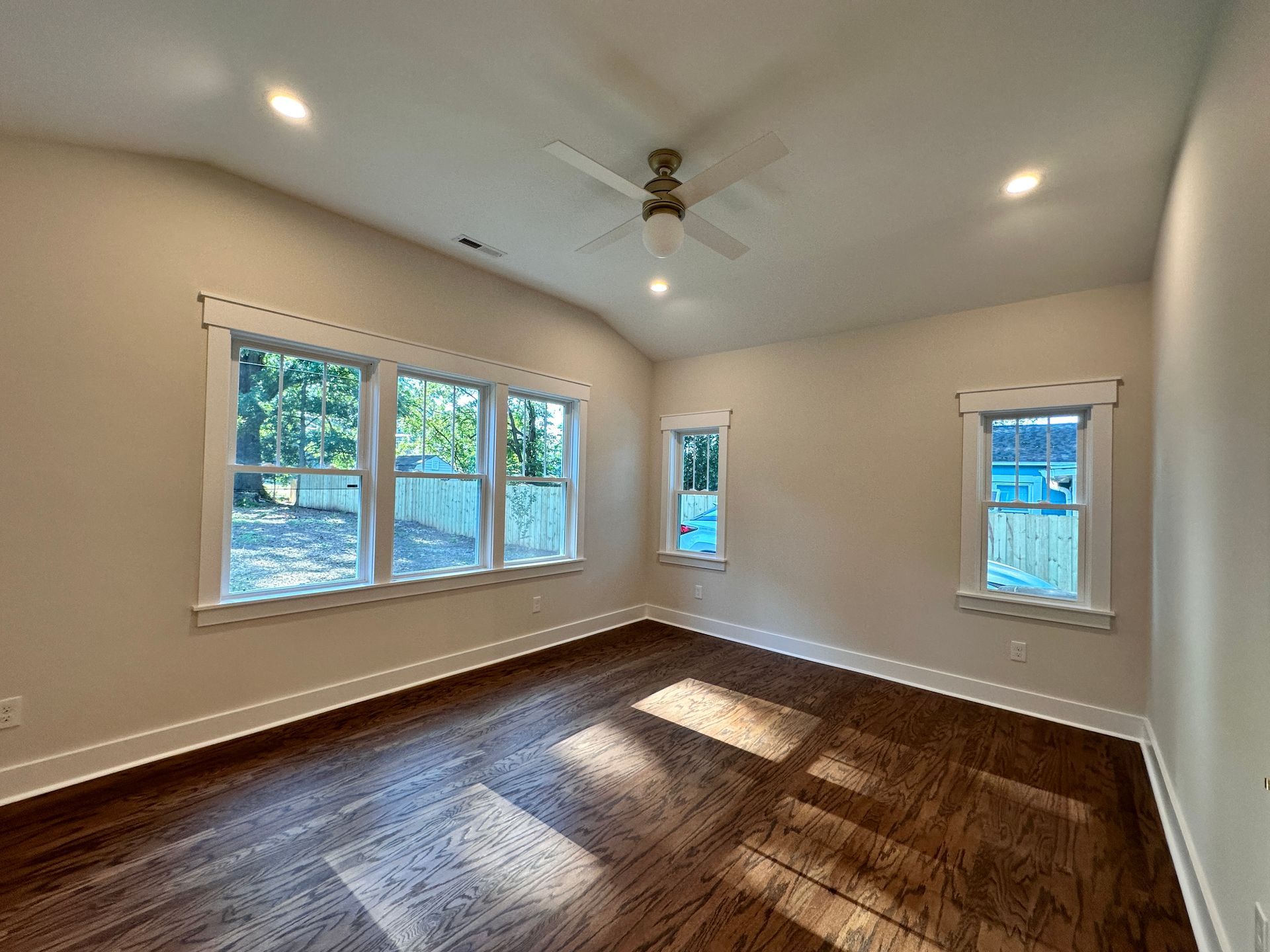 An empty room with hardwood floors and a ceiling fan.