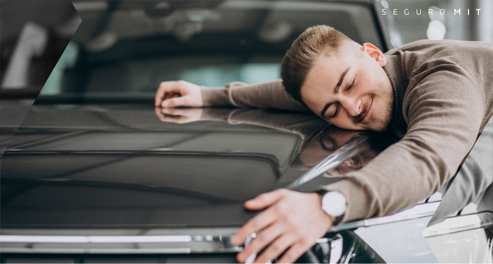 Um homem está deitado no capô de um carro.