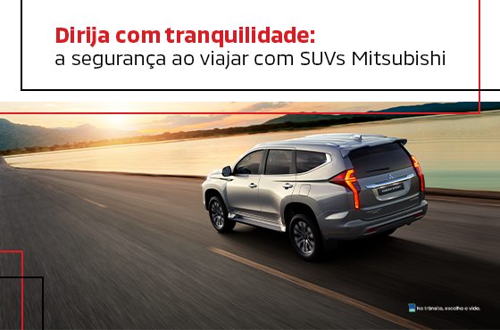 Um SUV prateado está dirigindo por uma estrada.