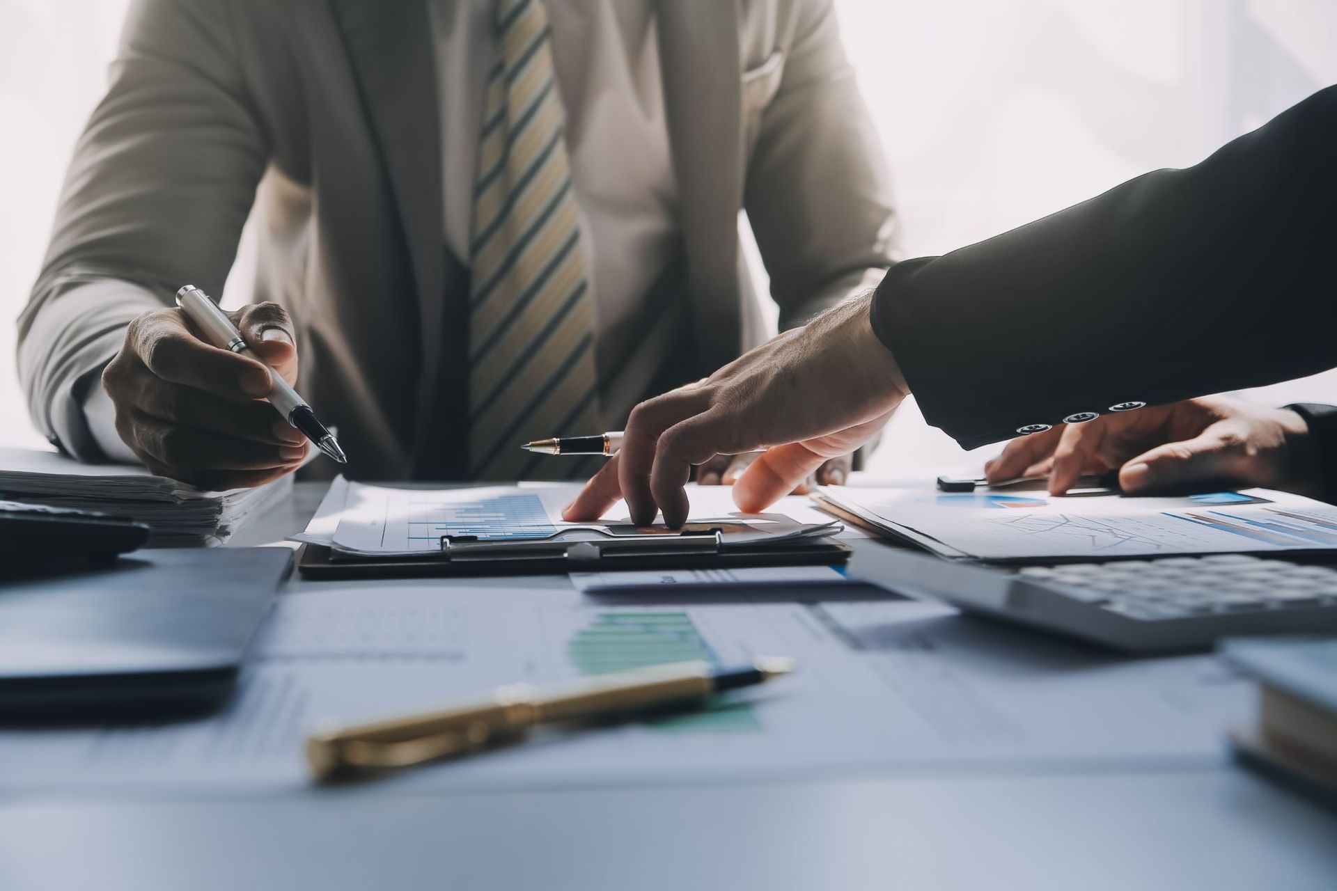 Two people in business attire reviewing documents at a table, one pointing with a pen.