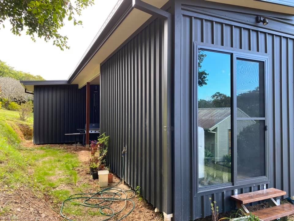 A Black House With A Sliding Glass Door And Stairs In Front Of It — Nambucca Construction In Nambucca Heads, NSW