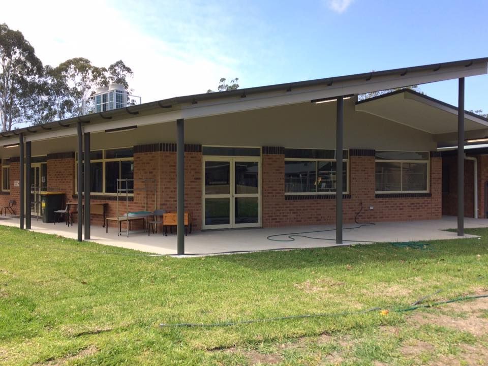 A Large Brick Building With A Covered Porch And A Lot Of Windows — Nambucca Construction In Nambucca Heads, NSW