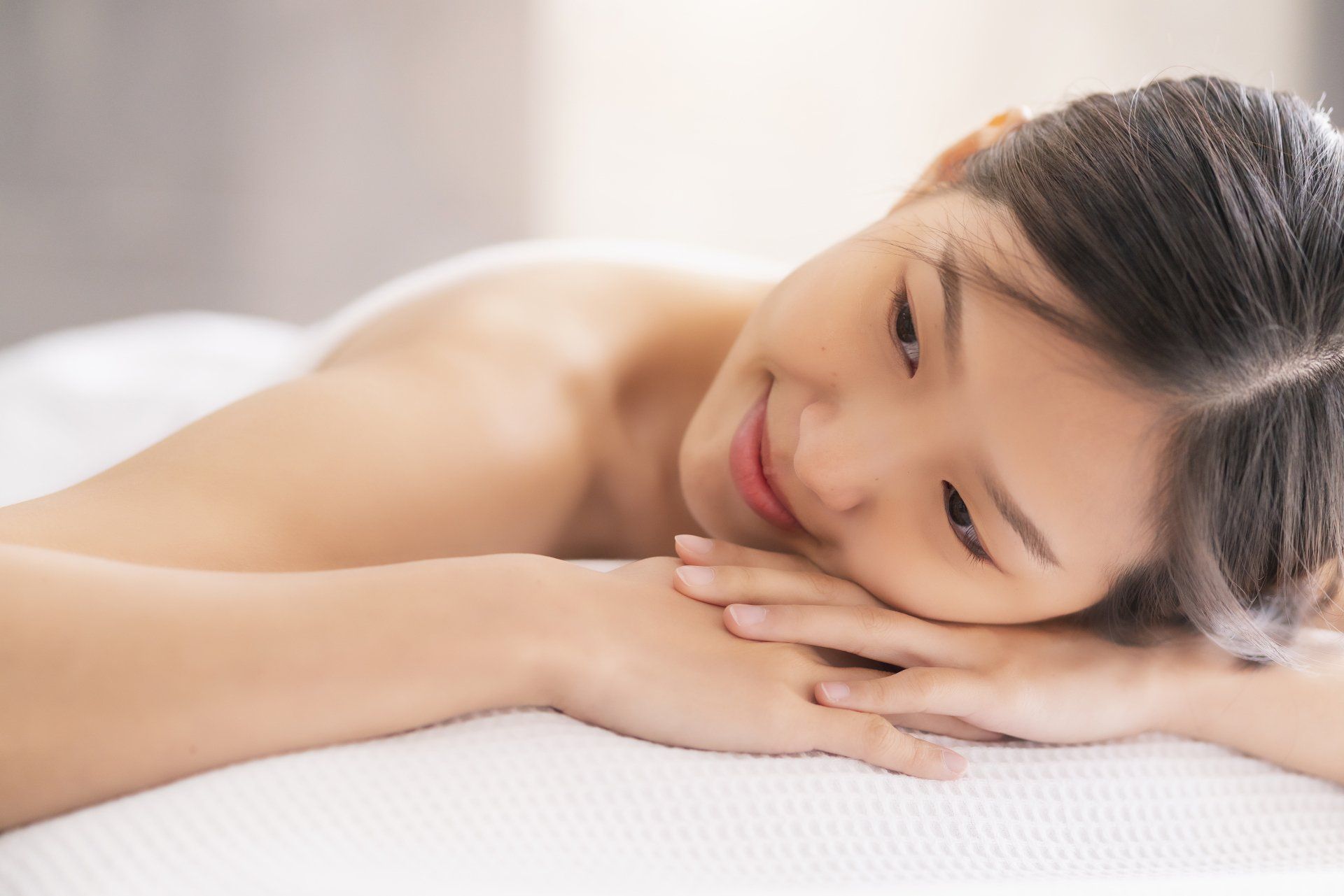 a beautiful Asian woman lying on a massage table
