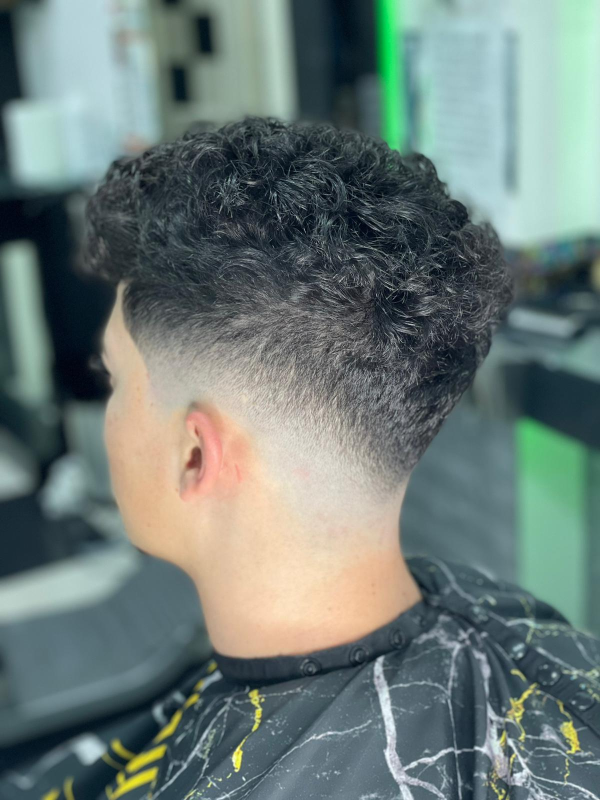 Un uomo con i capelli ricci si fa tagliare i capelli dal barbiere.