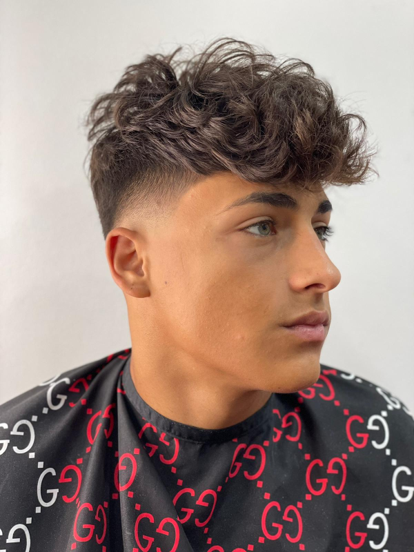 Un giovane con i capelli ricci indossa un mantello Gucci