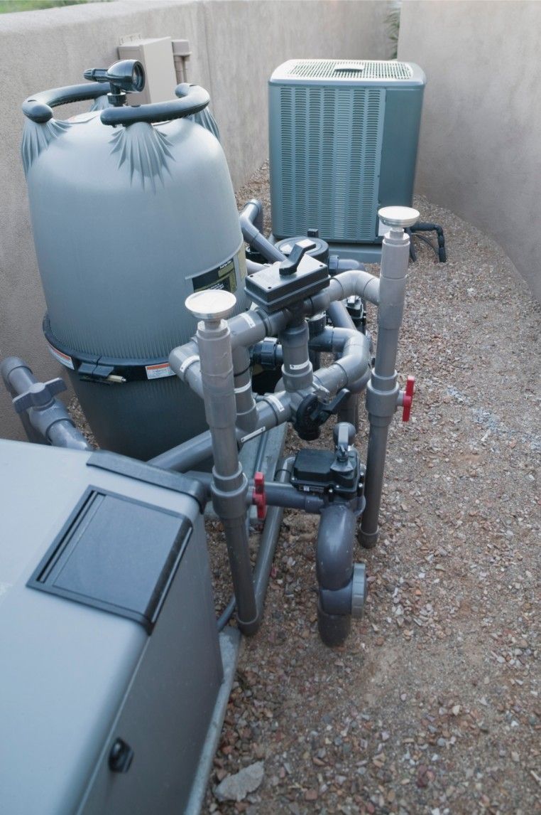 A swimming pool equipment is sitting next to a pool heater.