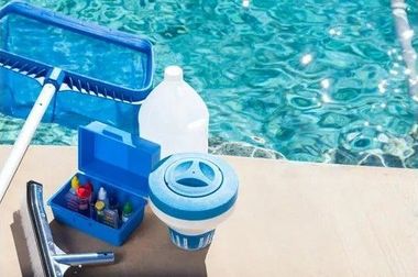 A pool cleaning kit is sitting next to a swimming pool.