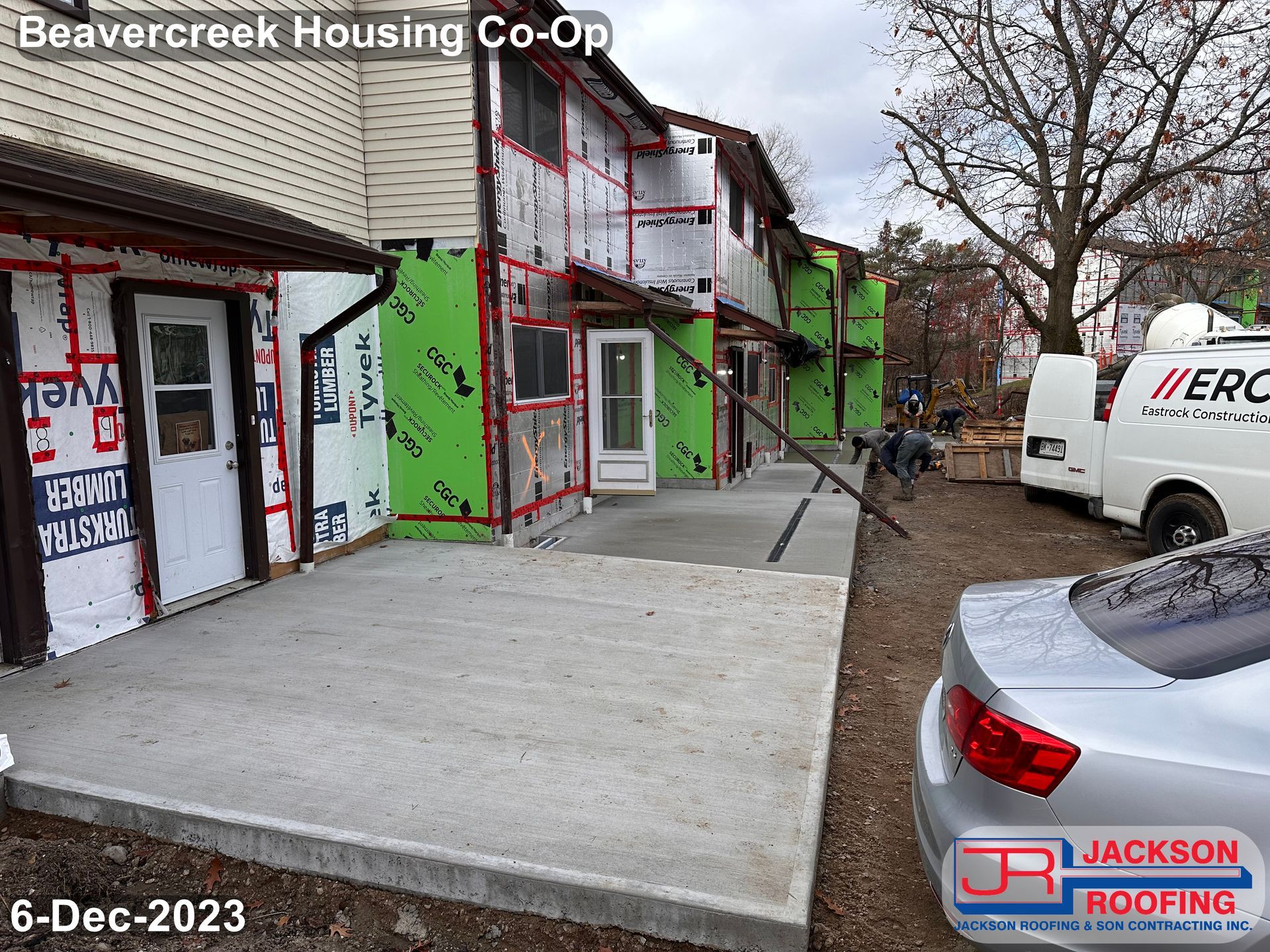 A car is parked in front of a building that is under construction.