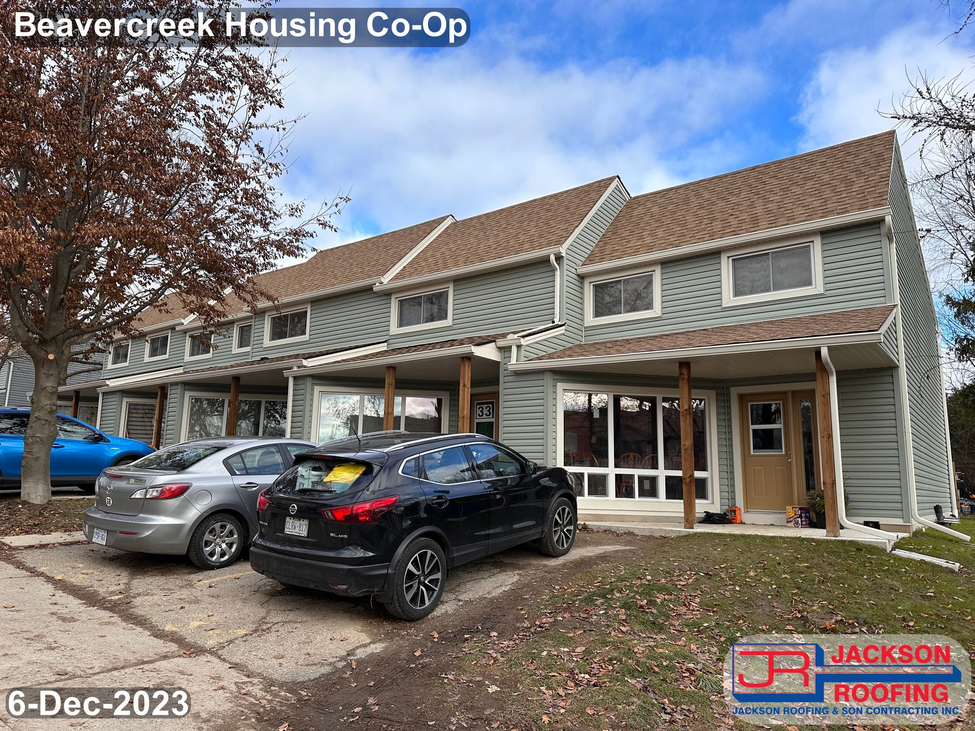 A row of houses with cars parked in front of them.