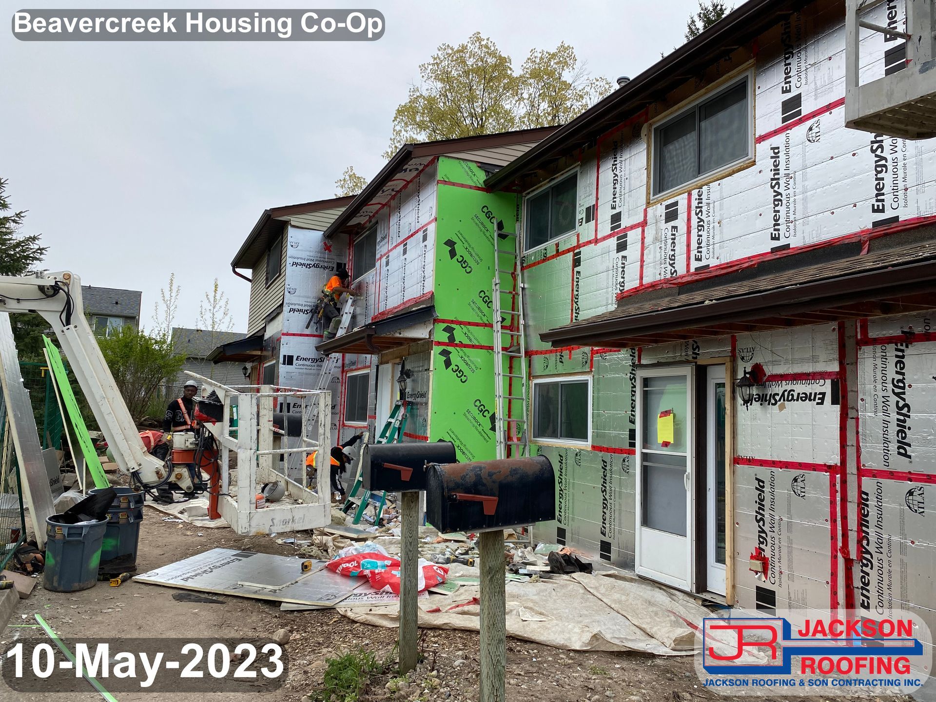 A picture of a building under construction with a mailbox in front of it.