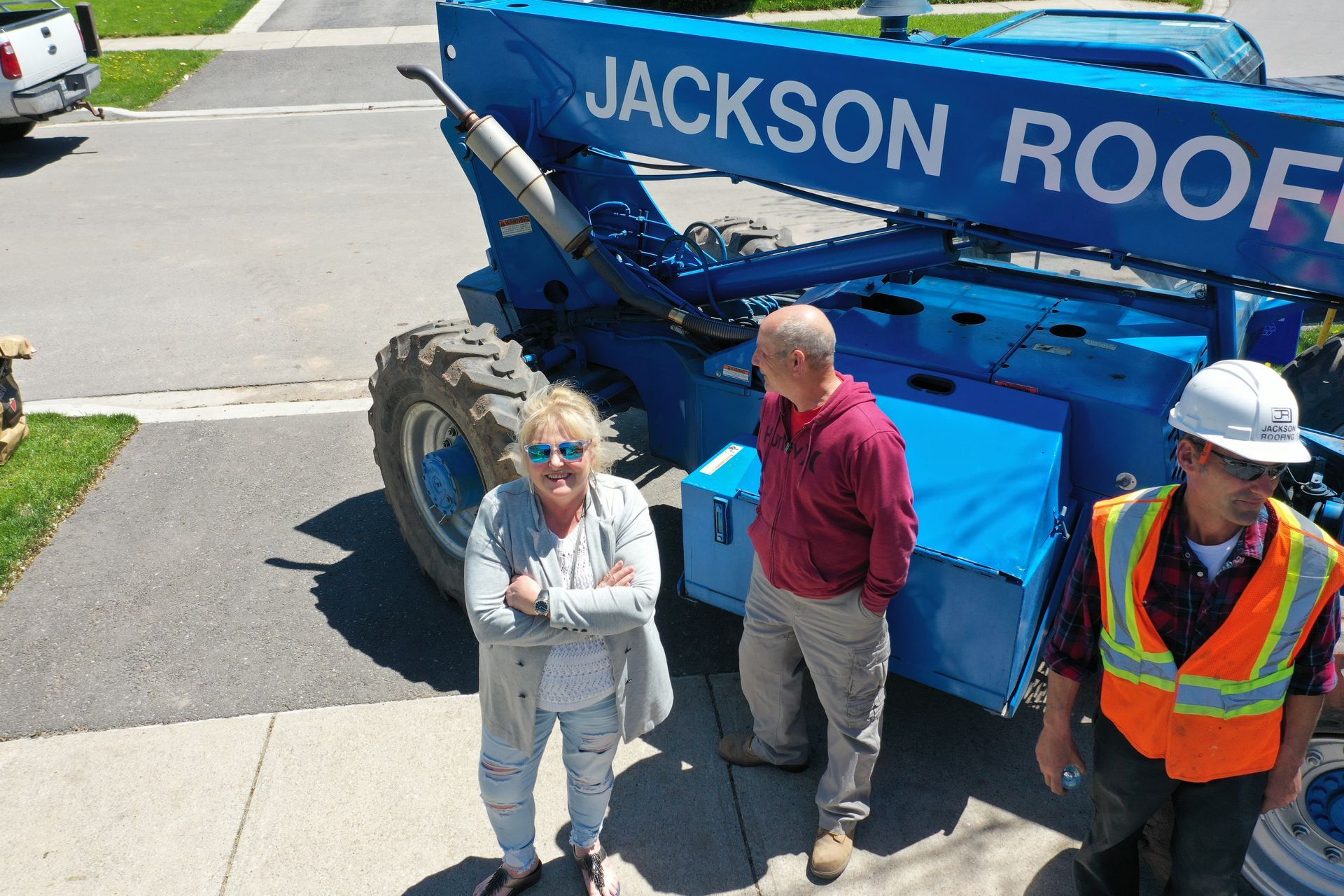 A woman and two men are standing in front of a jackson roofing machine.