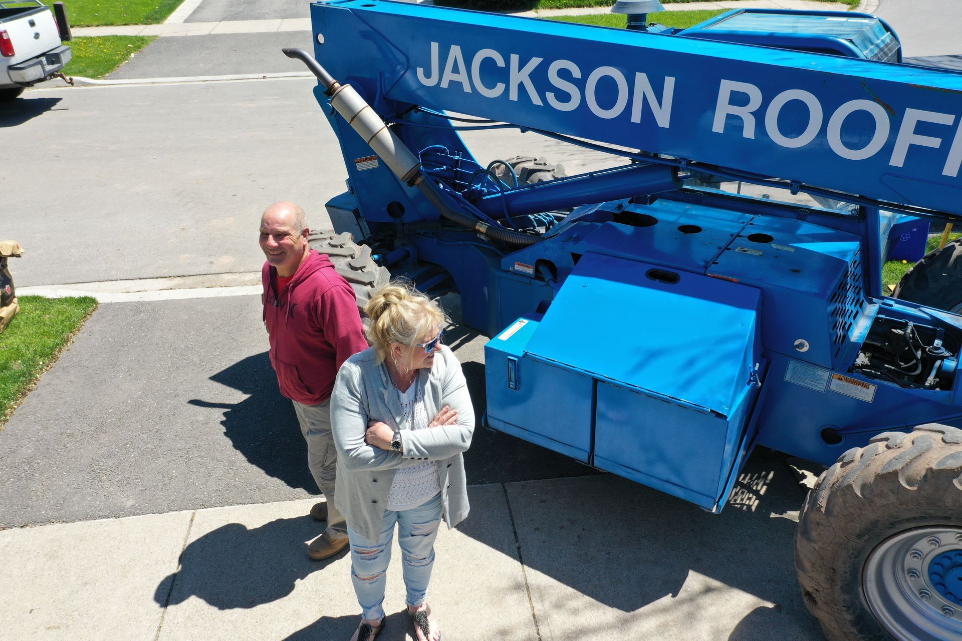 A man and a woman are standing in front of a jackson roofing machine