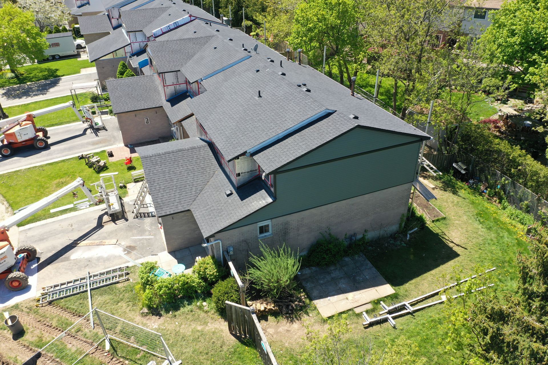 An aerial view of a row of houses with a roof being installed.