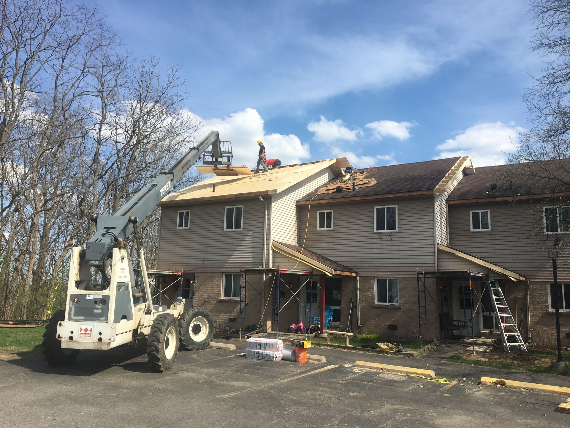 A white forklift is parked in front of a building that is being remodeled.
