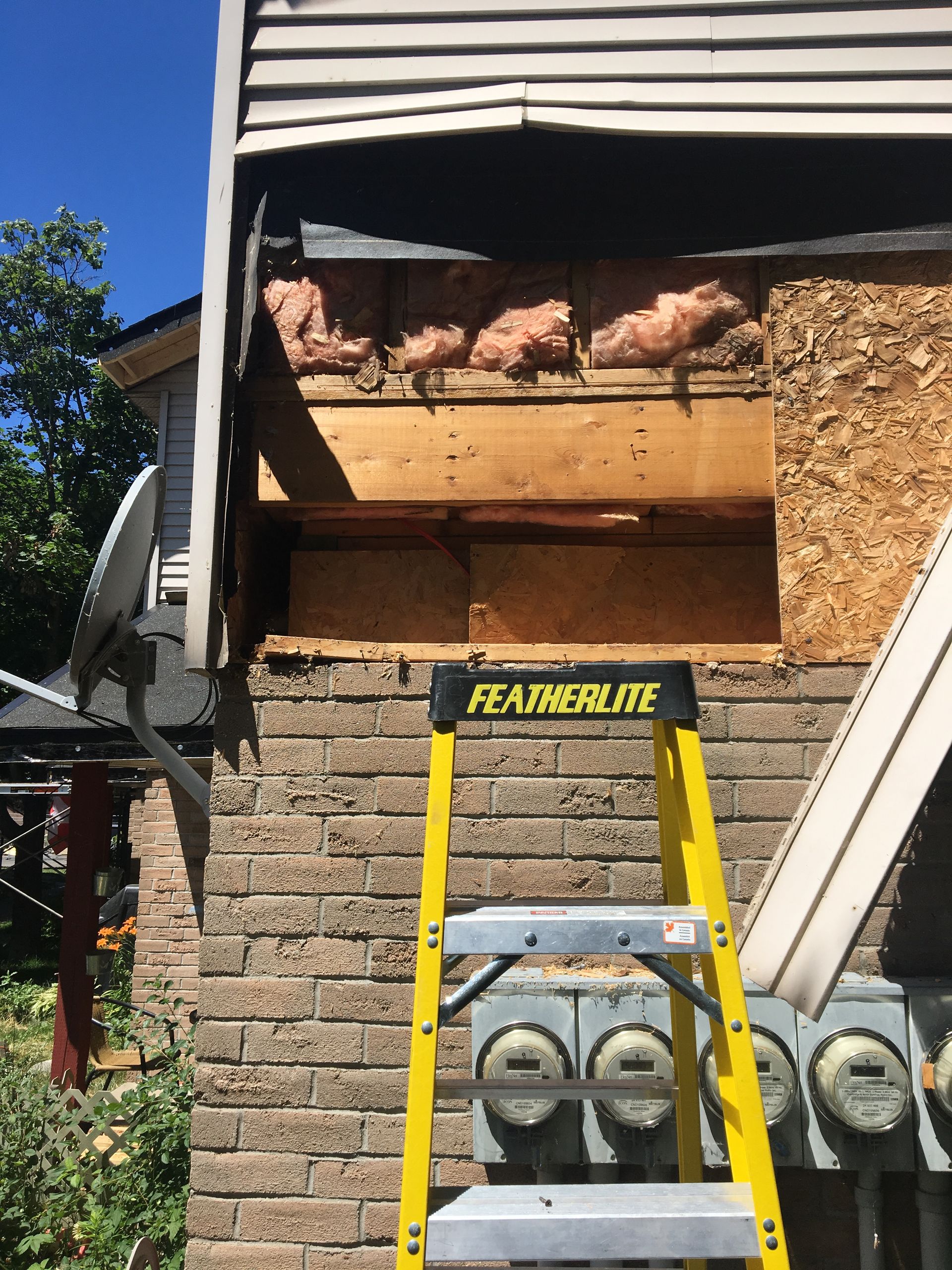 A yellow ladder is sitting on the side of a brick building.