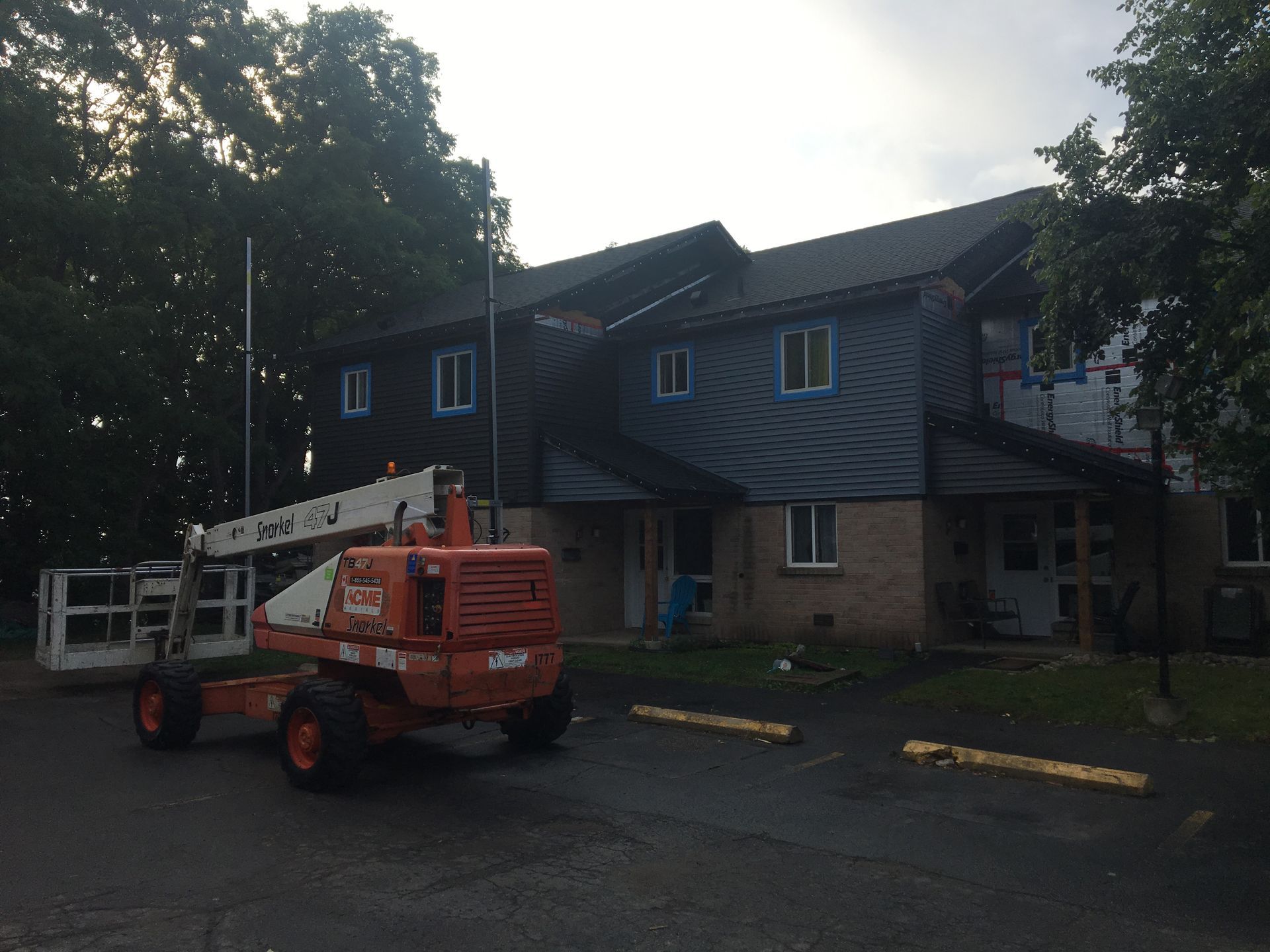 An orange jlg lift is parked in front of a building