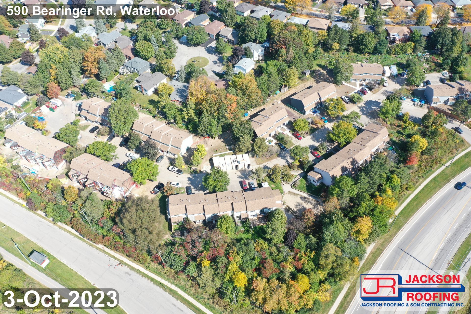 An aerial view of a residential area with a highway and trees.