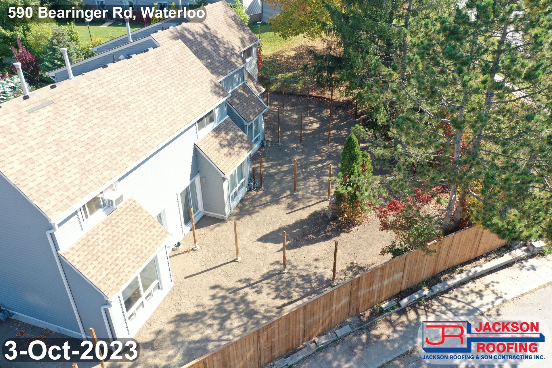 An aerial view of a house with a wooden fence in front of it.
