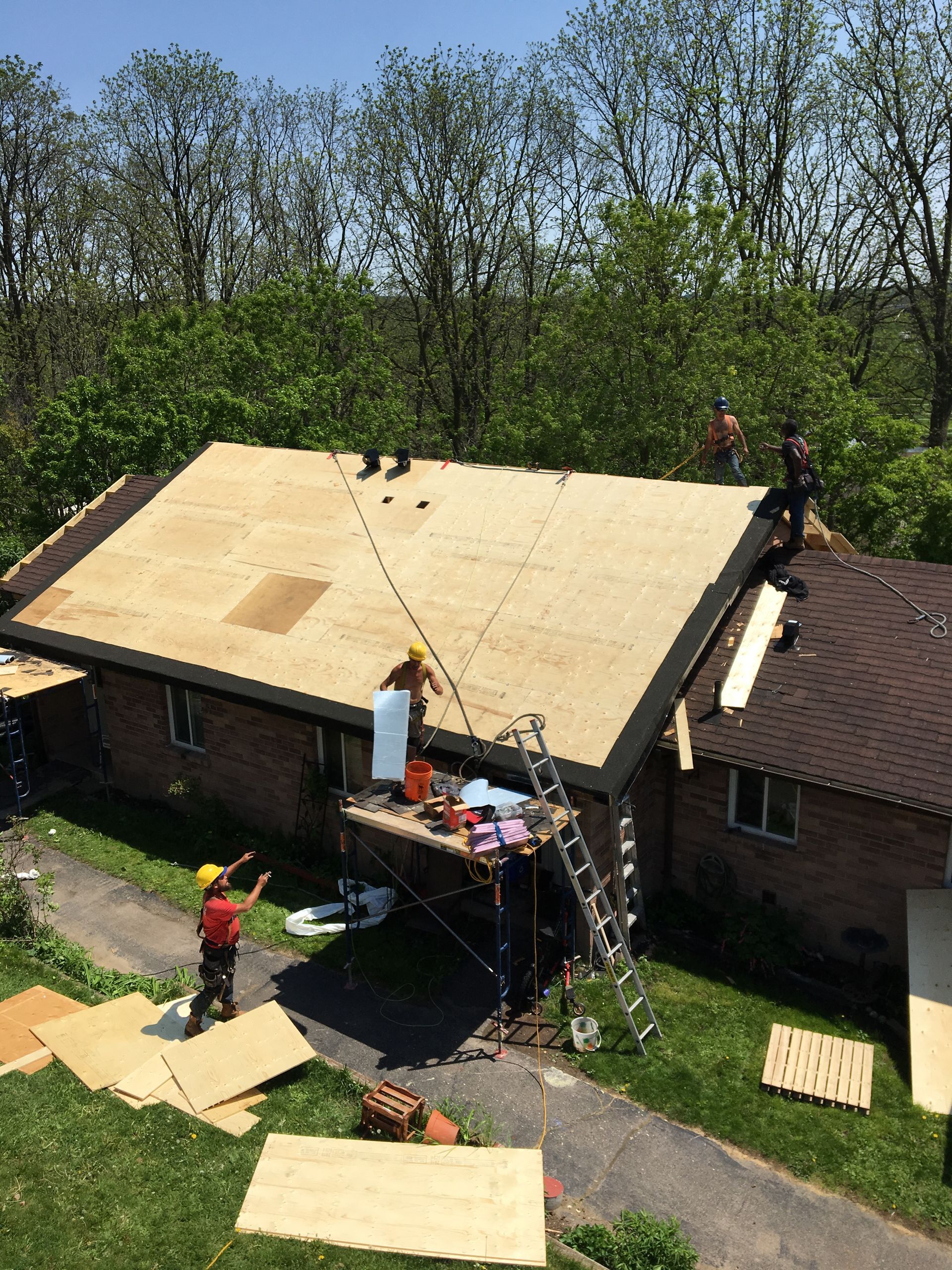 A group of people are working on the roof of a house.