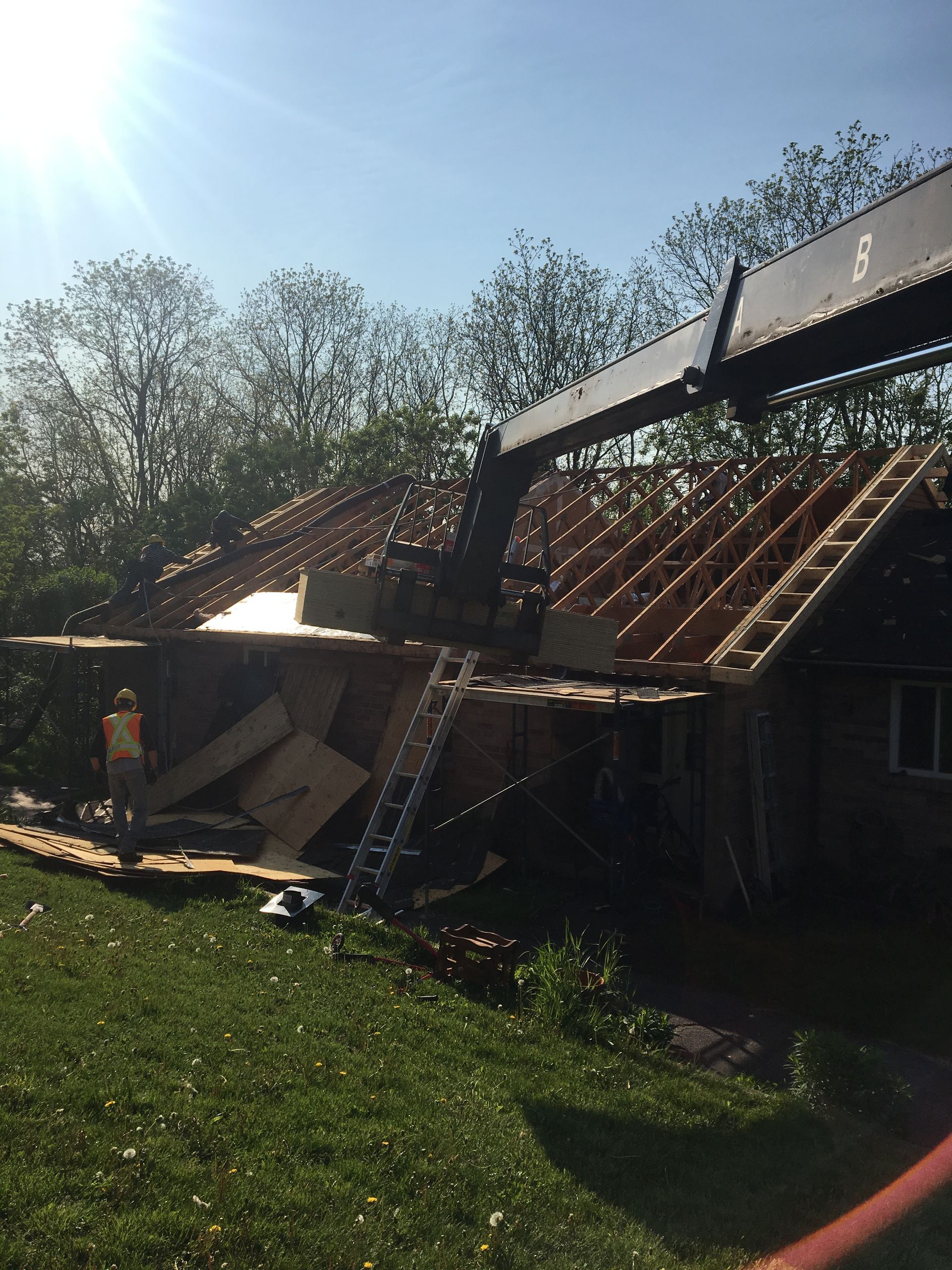 A crane is lifting the roof of a house