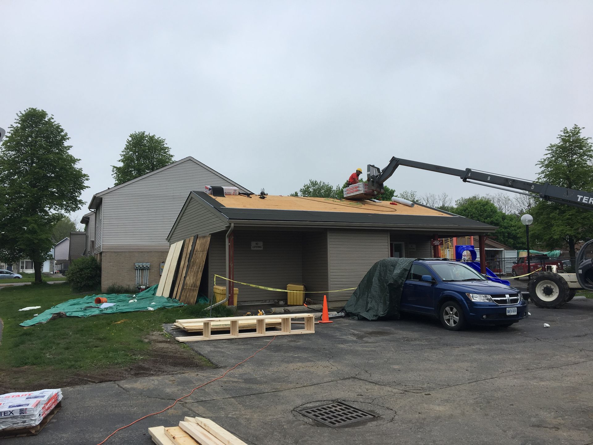 A blue car is parked in front of a house being remodeled.