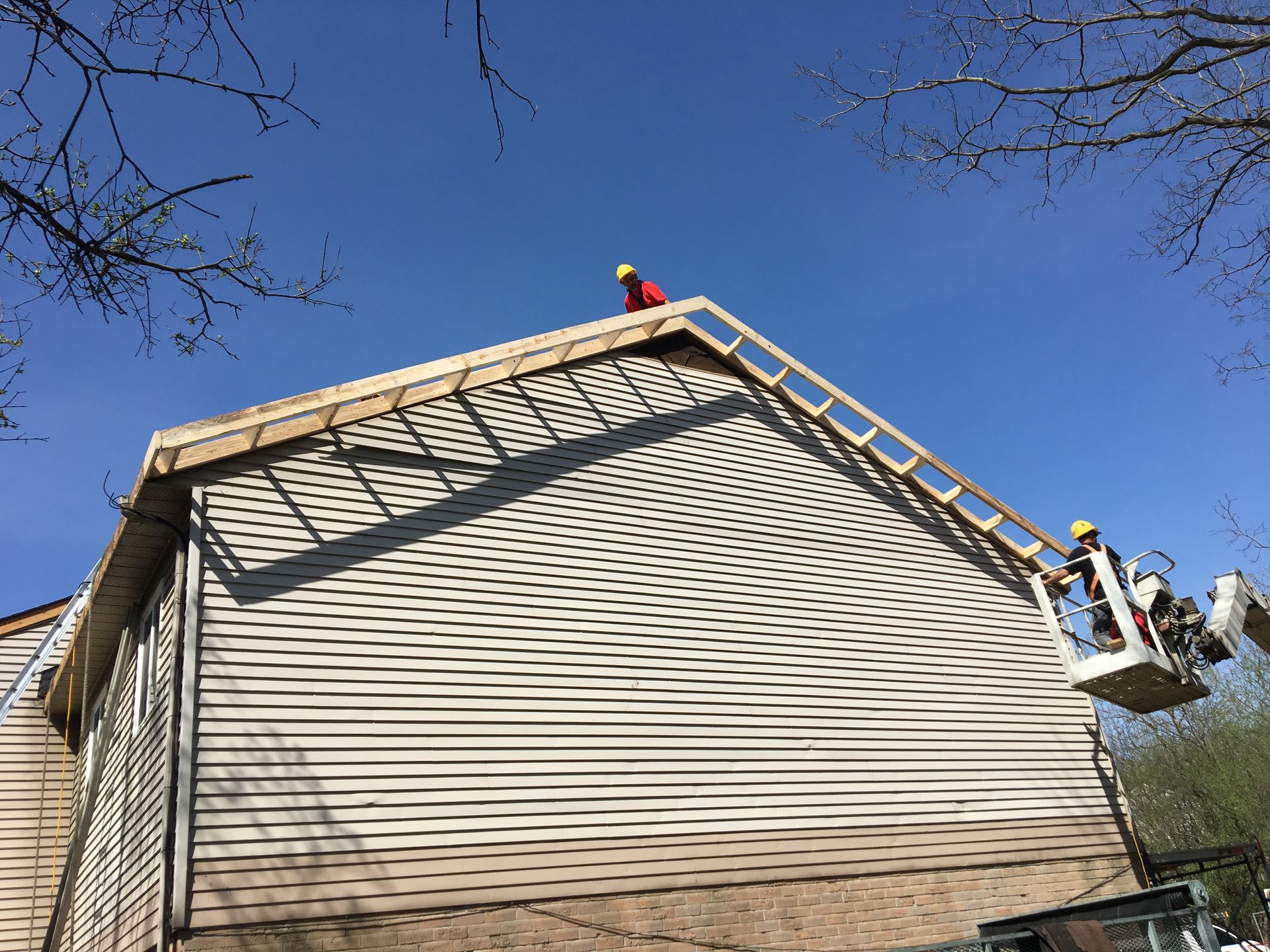 A man is standing on a ladder on top of a house.