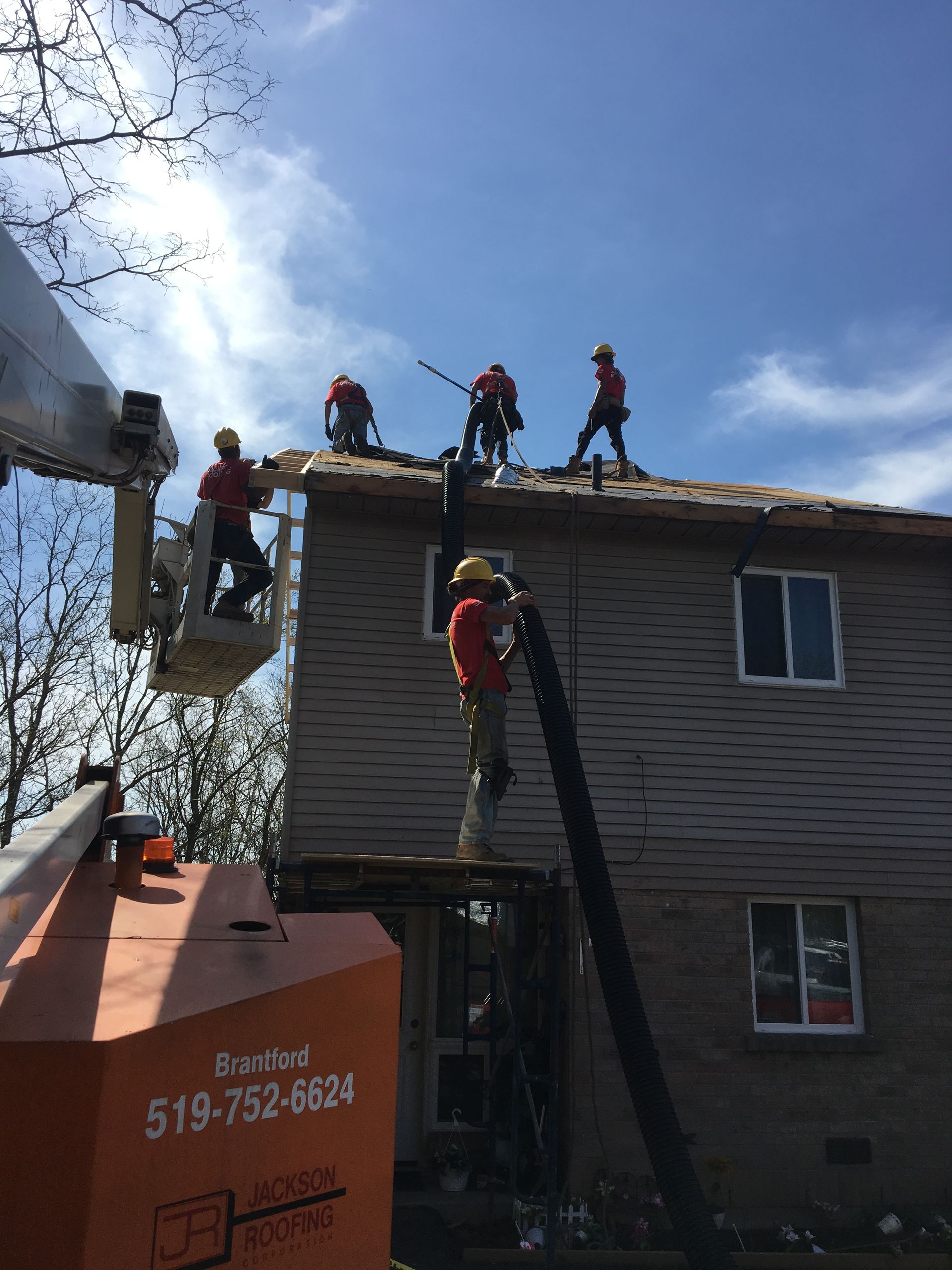 A group of construction workers are working on the roof of a house.