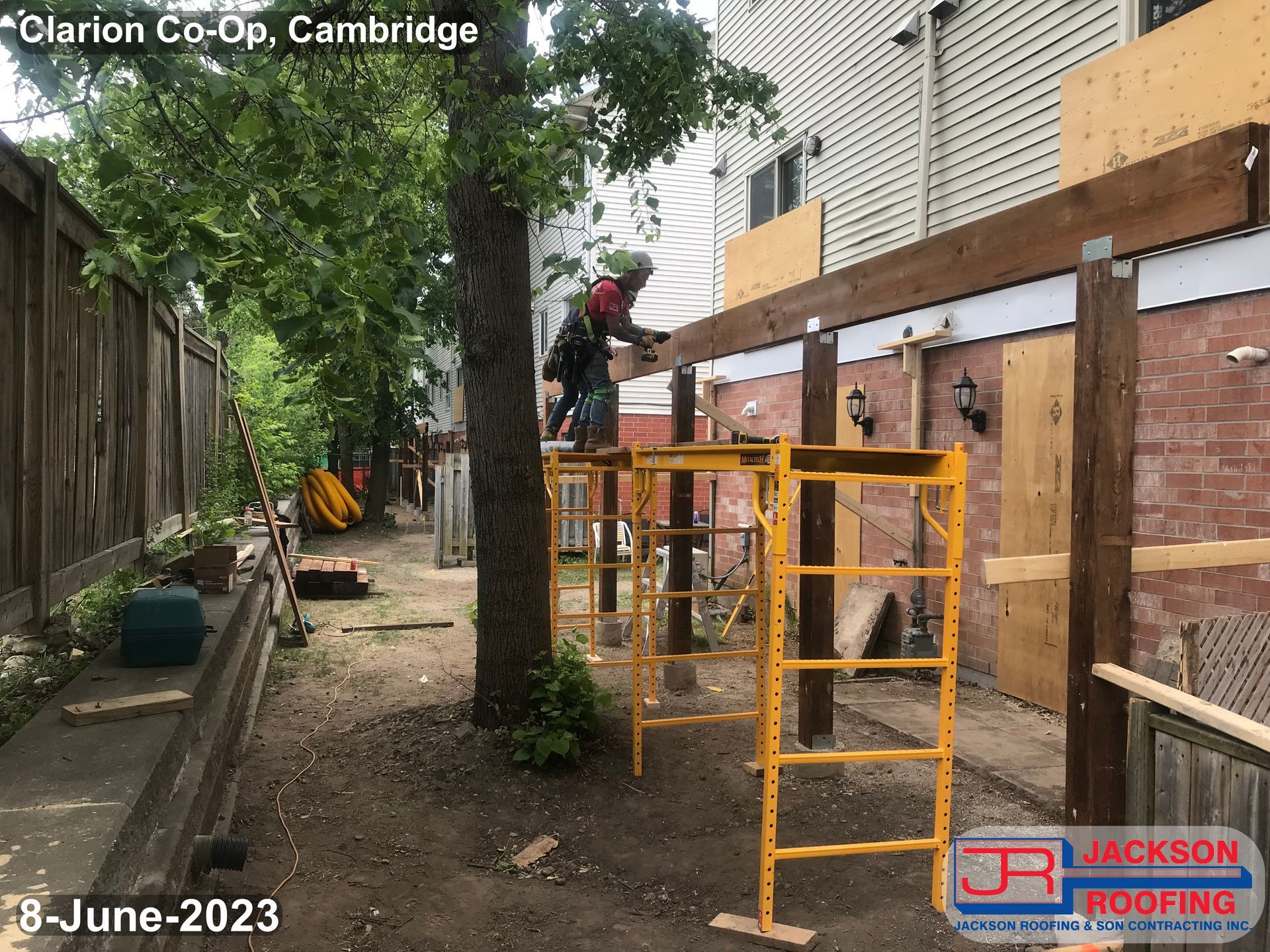 A man is standing on a scaffolding in front of a house.