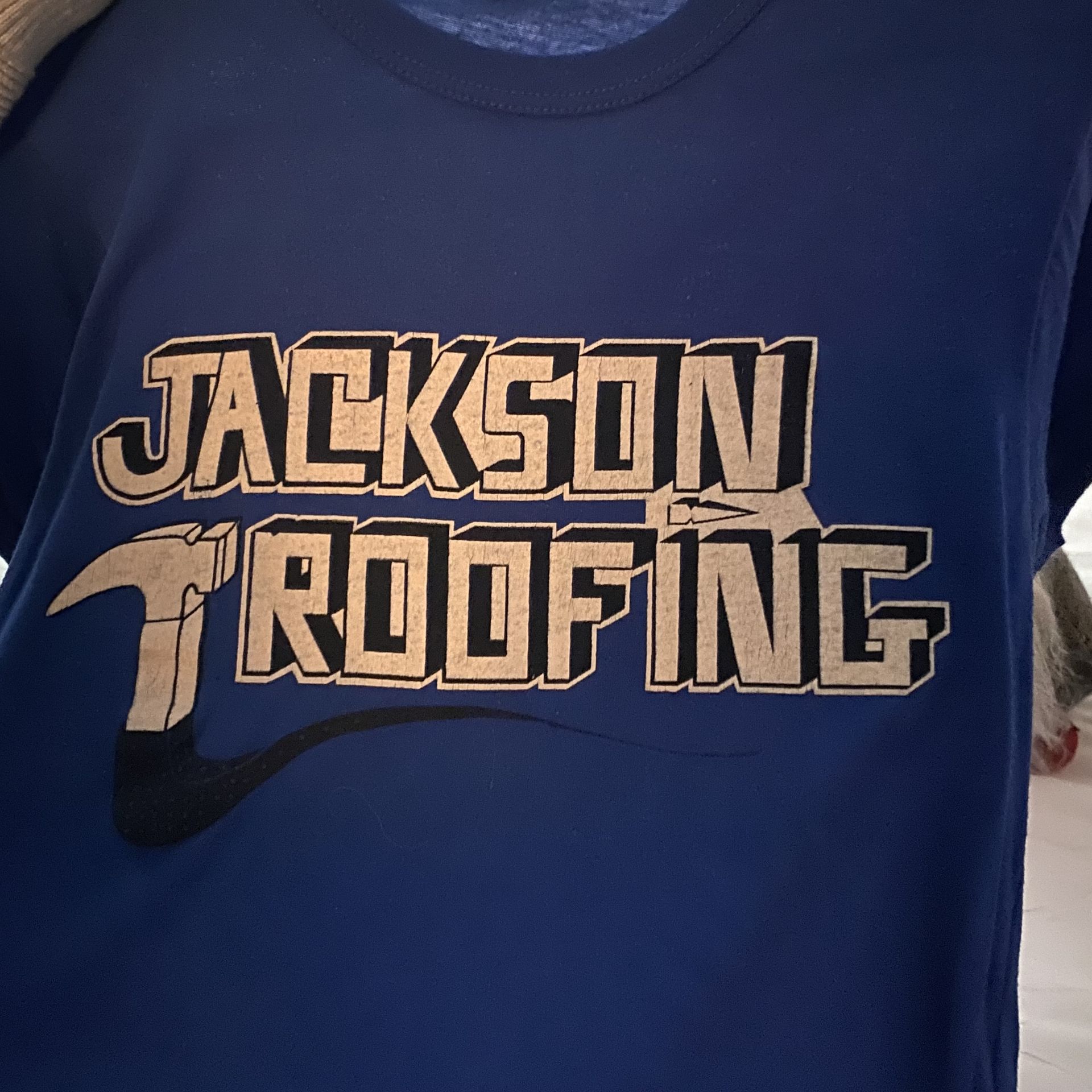A blue shirt that says jackson roofing on it