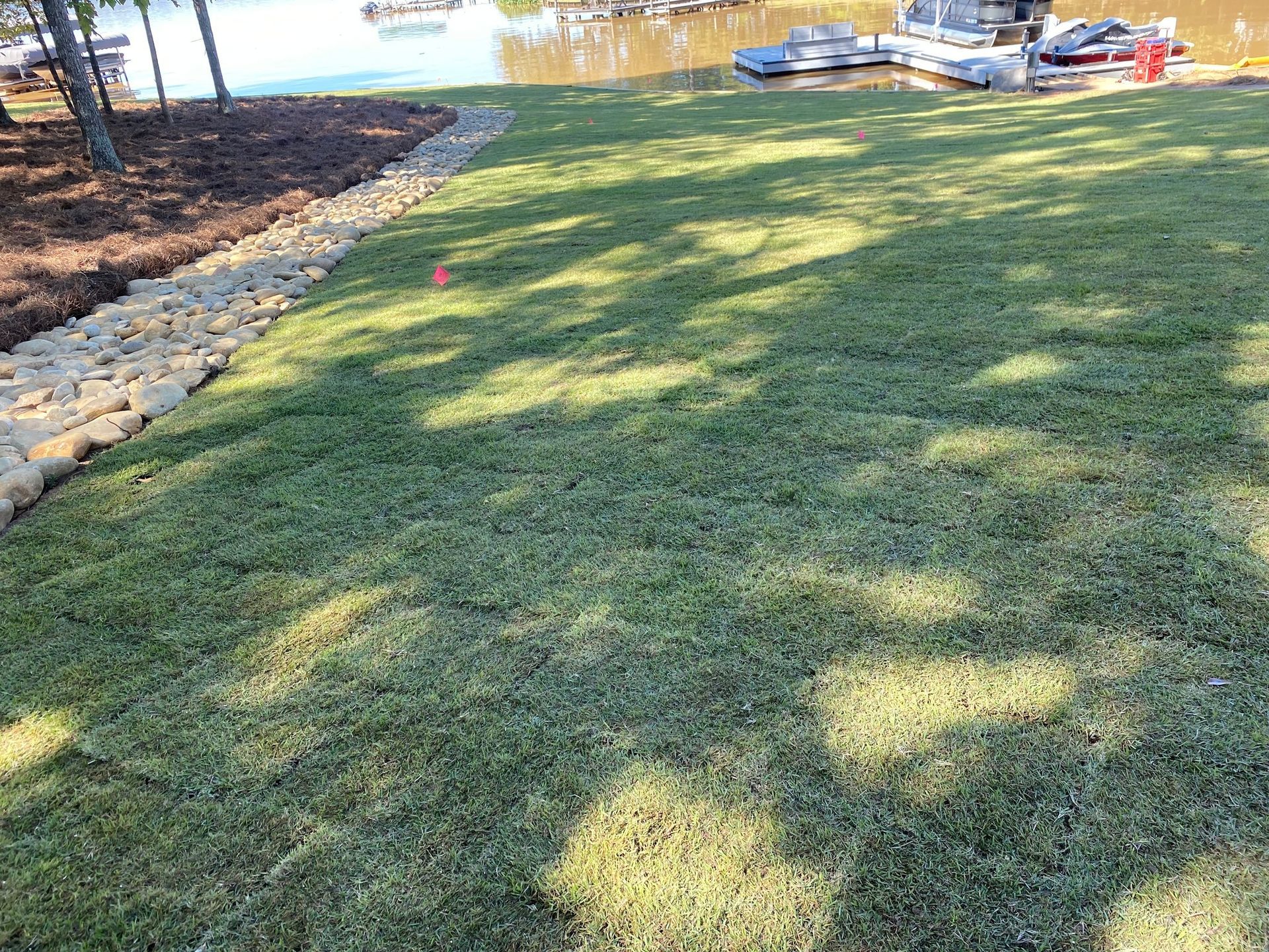 A lush green lawn next to a body of water.