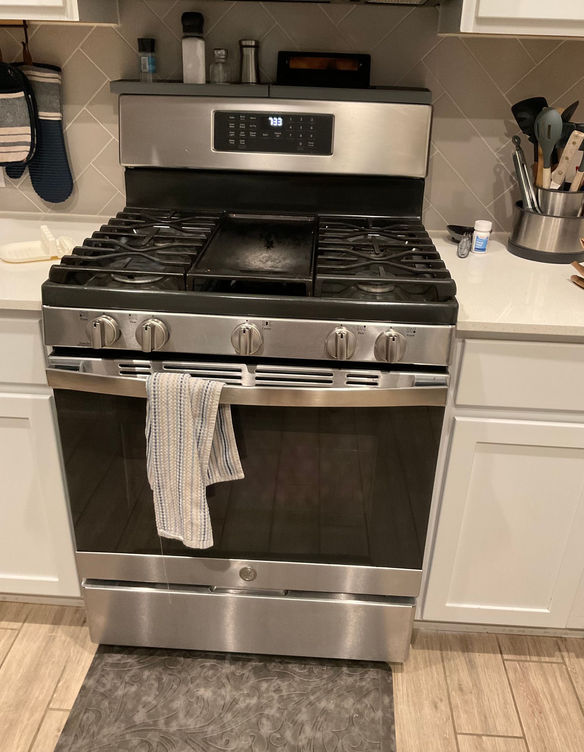 Stainless steel gas range with griddle in a kitchen.