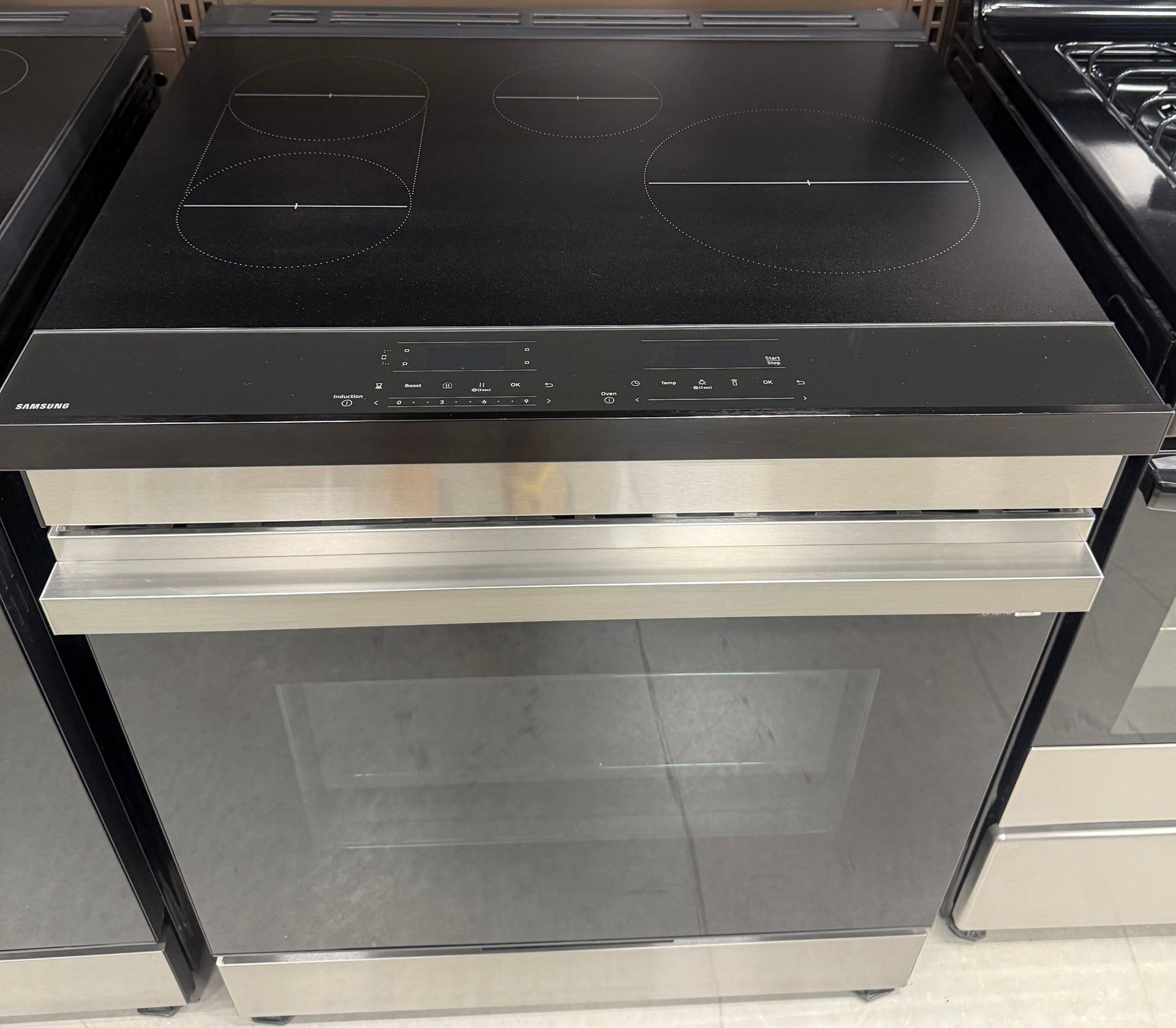 Stainless steel electric range with black cooktop and oven.