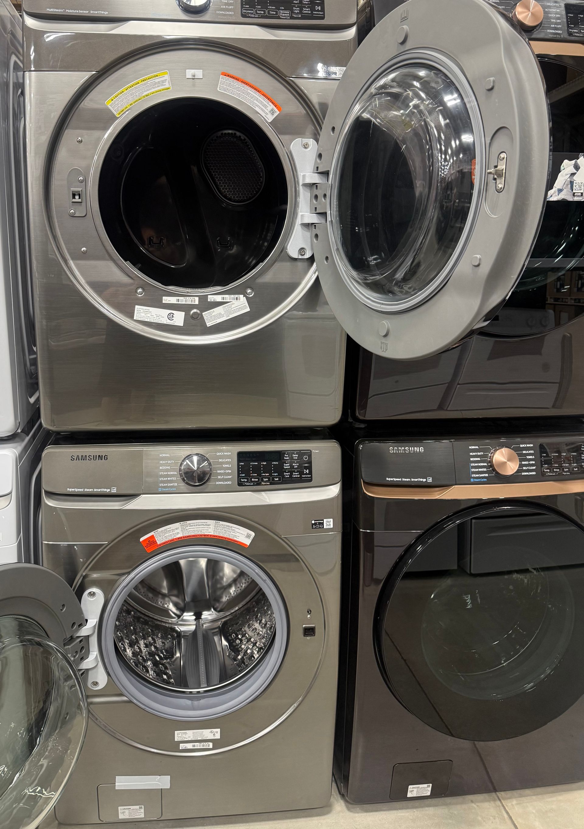 Several front-load washing machines stacked, some doors open, metallic colors.