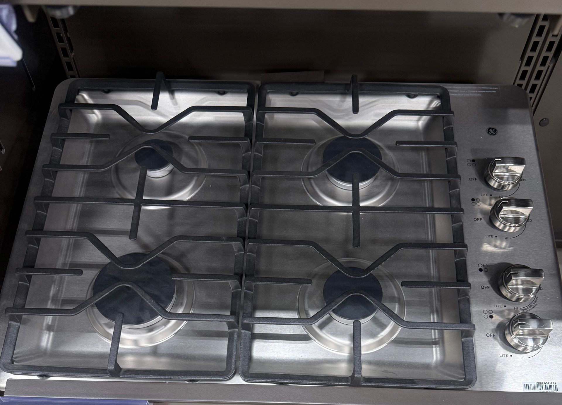 Stainless steel gas cooktop with four burners and black grates.