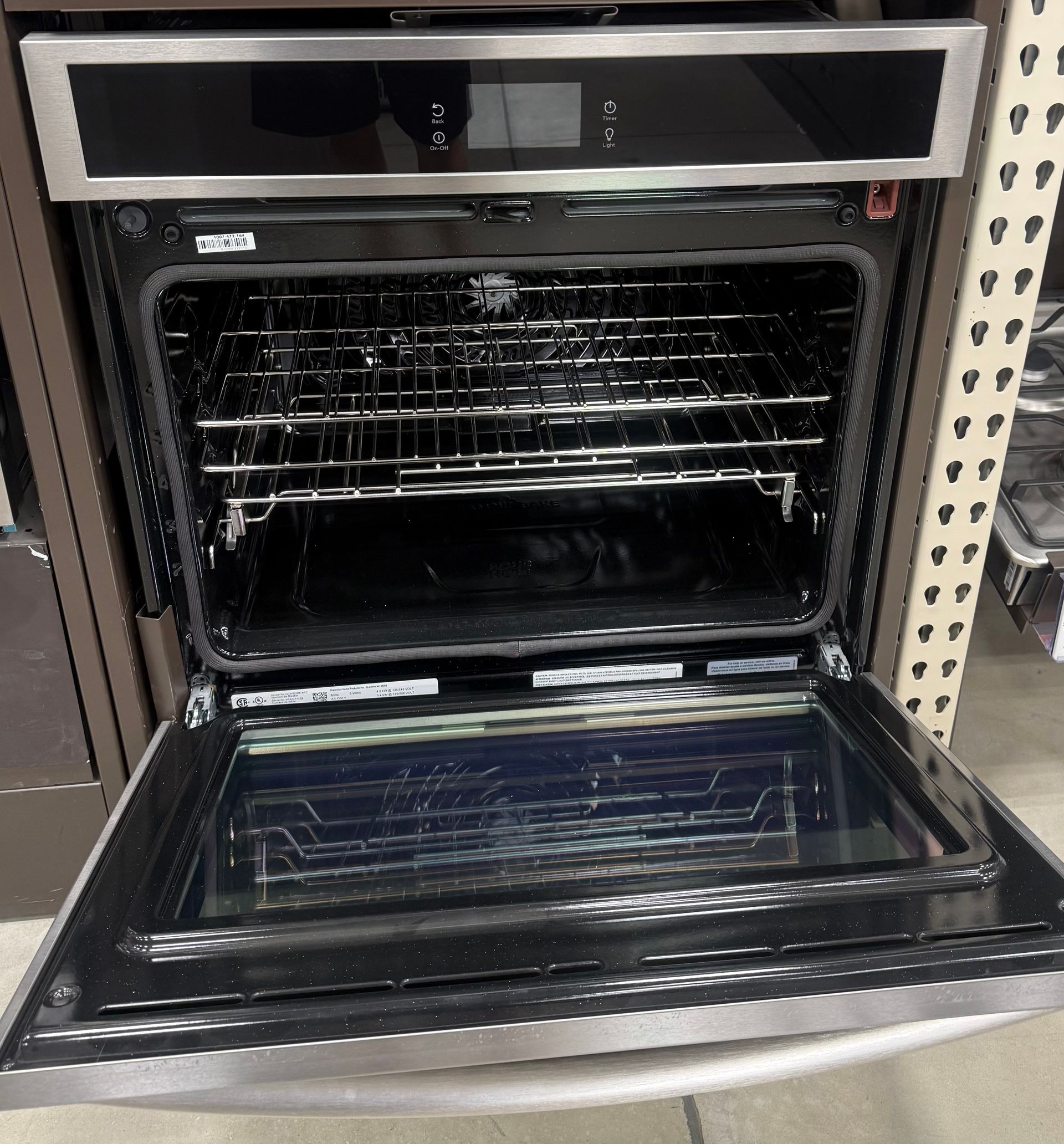 Stainless steel oven, door open, with interior racks visible.