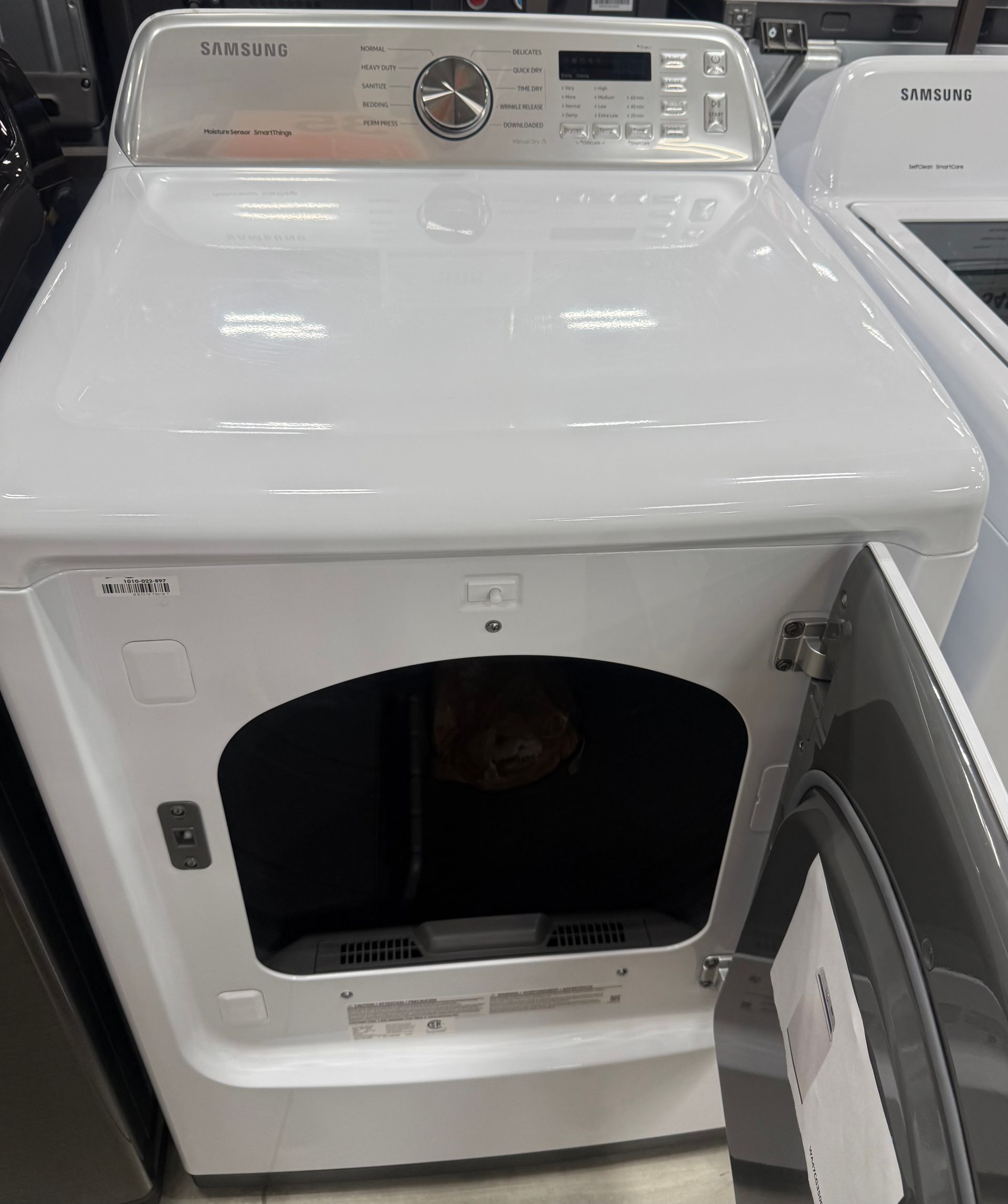 White Samsung dryer with open door in a store.