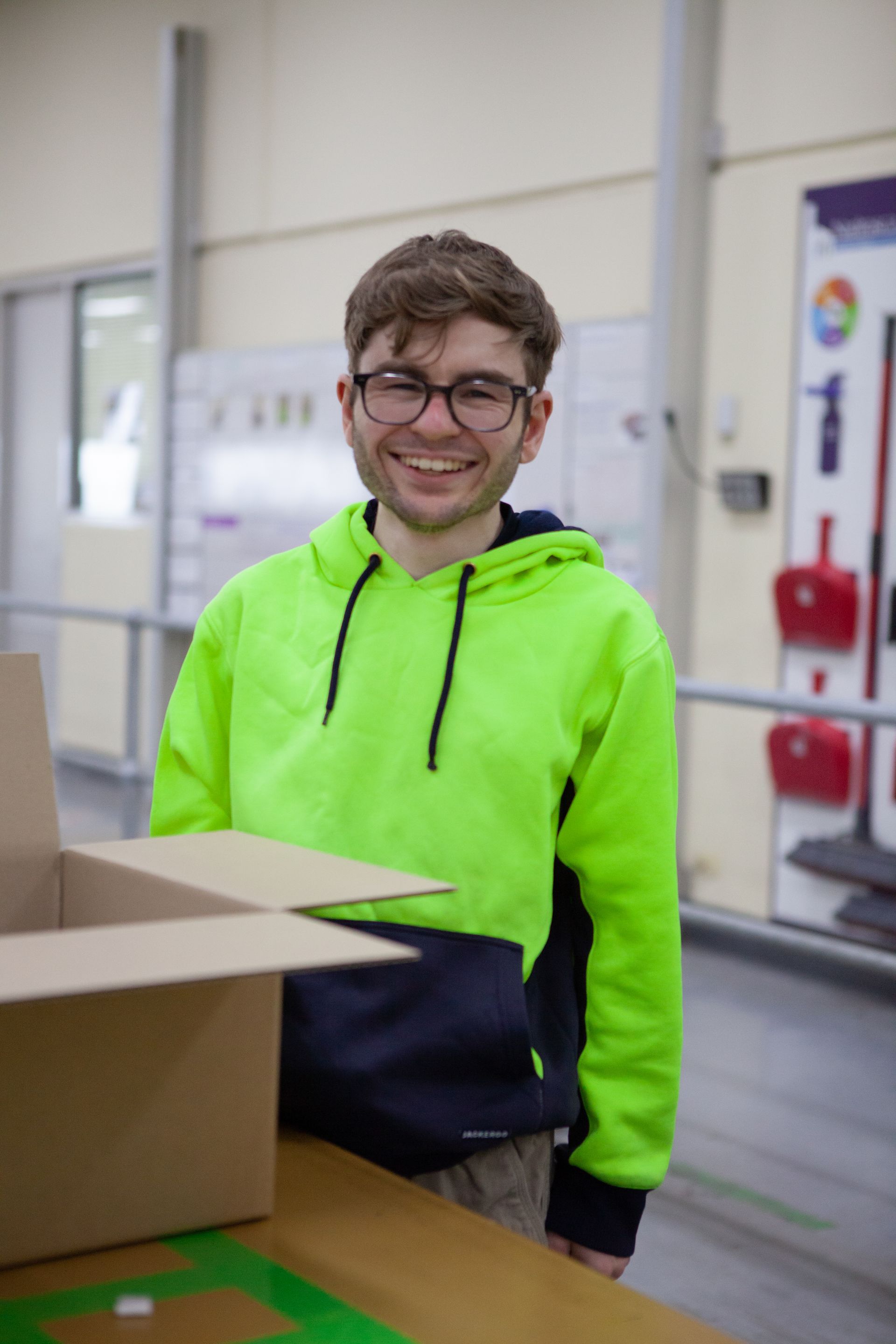 Young man standing and smiling as he packs boxes