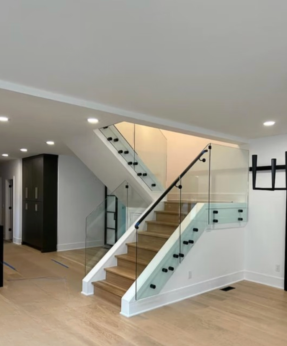 Modern home interior with white staircase, glass railing, and wood floors