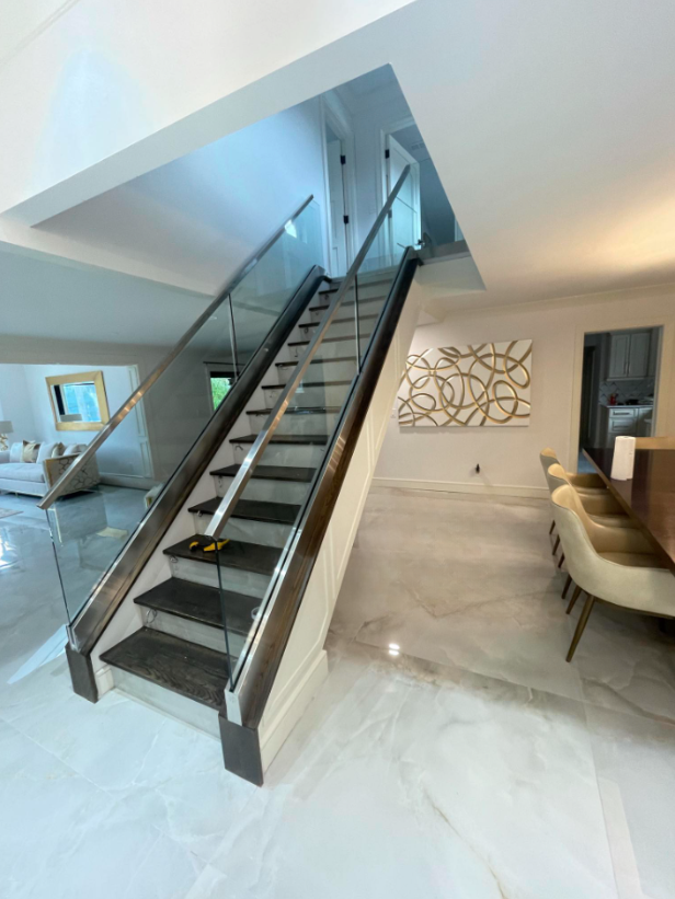 Modern interior with floating staircase, glass railing, and bright open living-dining area
