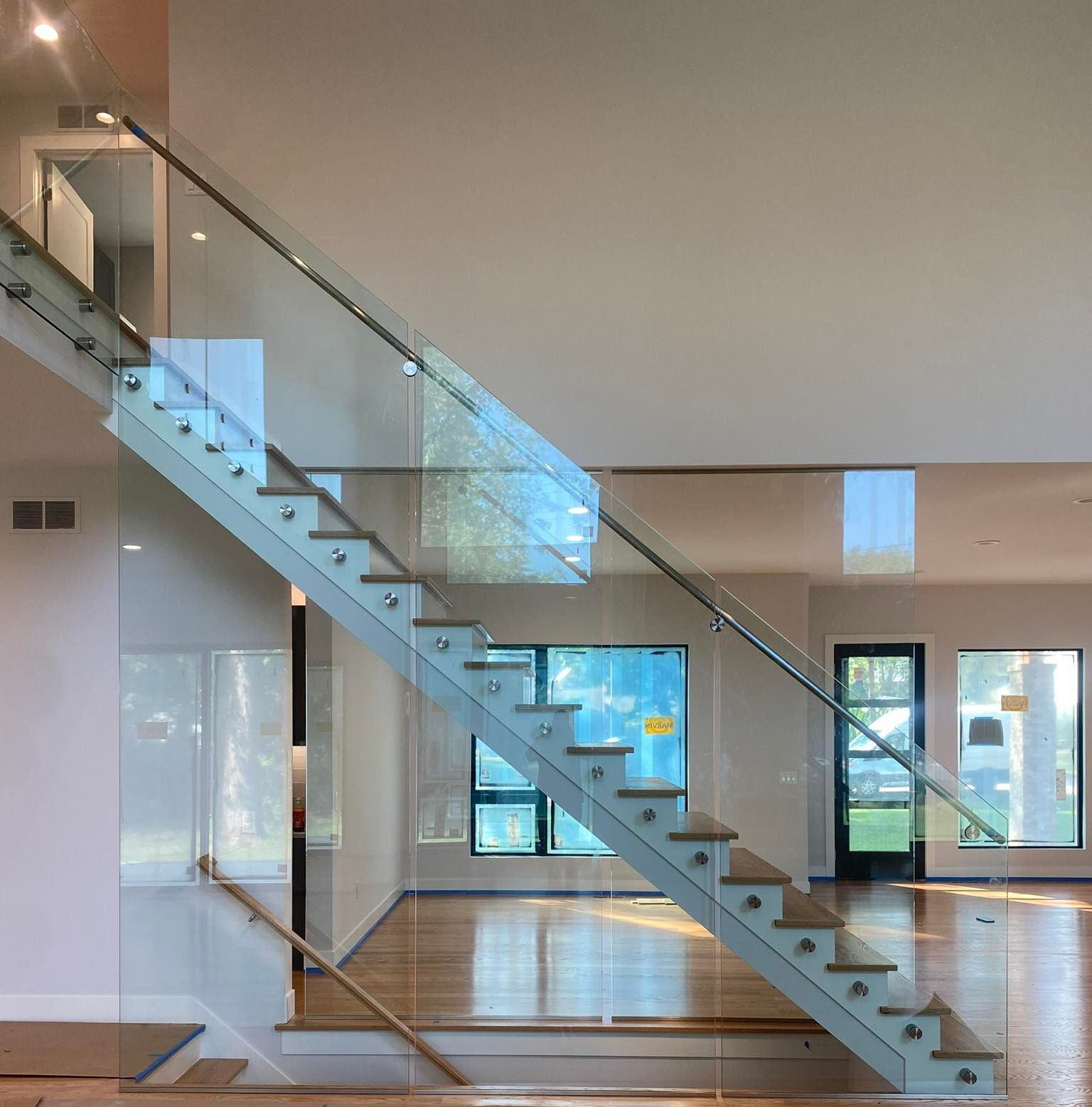 Modern interior with a glass staircase and wooden steps in a bright, minimalist home