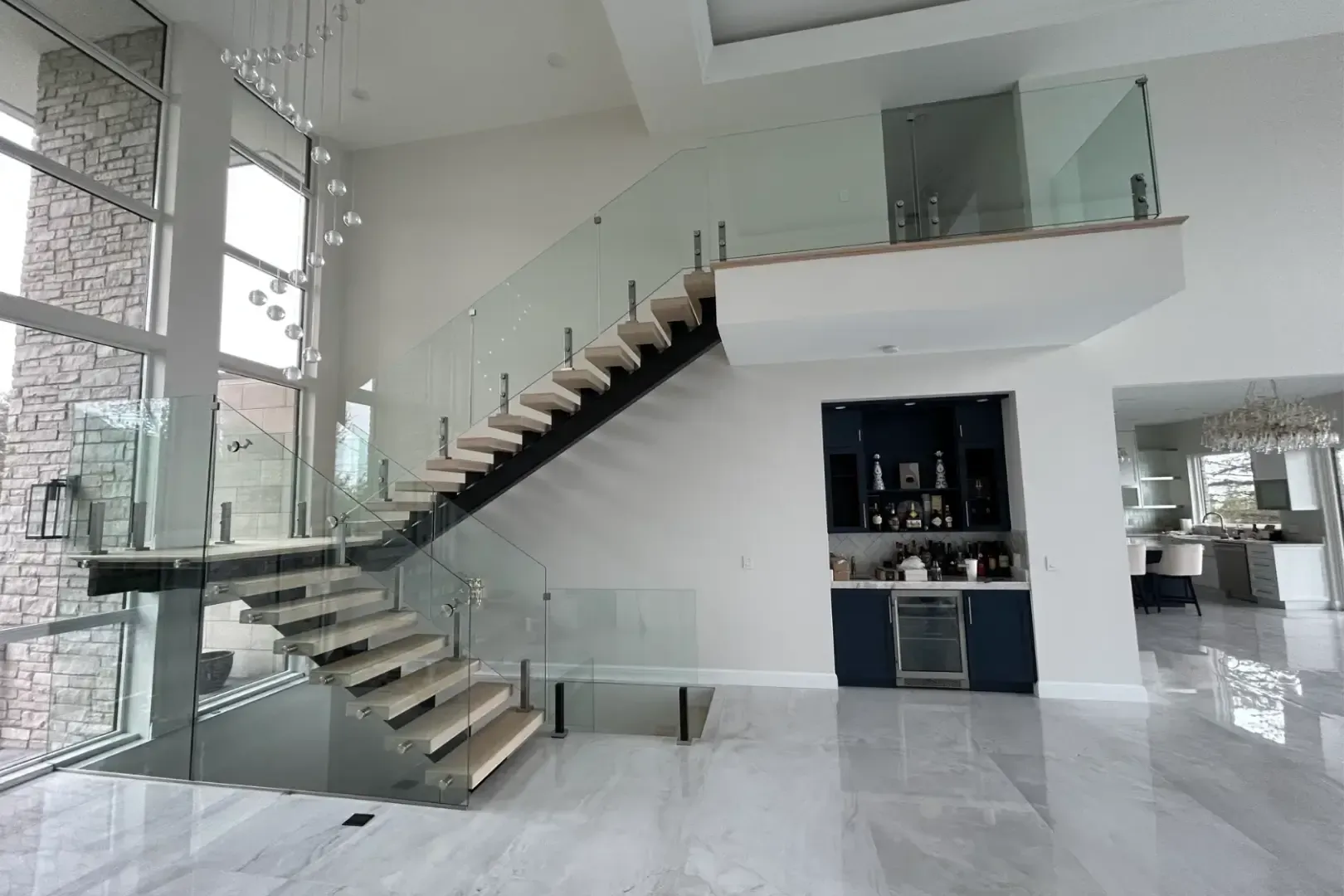 Modern luxury home interior with floating staircase, glass railings, and glossy white floors